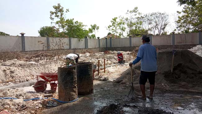 Seorang kuli sedang mengerjakan bangunan kios di SKEP R.P Moh Noer, Bangkalan