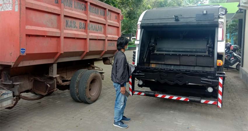 Salah seorang warga melintas didepan mobil compactor